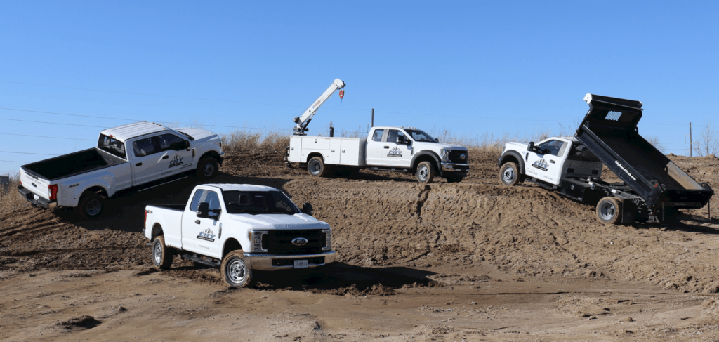 Various types of vehicles sitting on a dirt pad