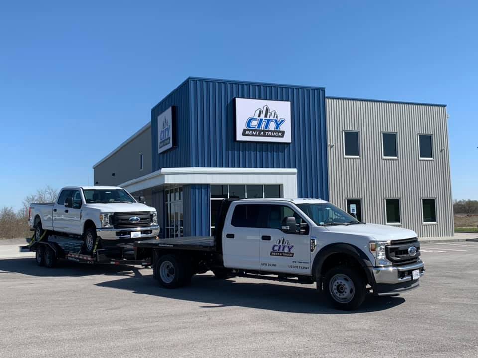 Truck towing another truck outside City Rent a Truck